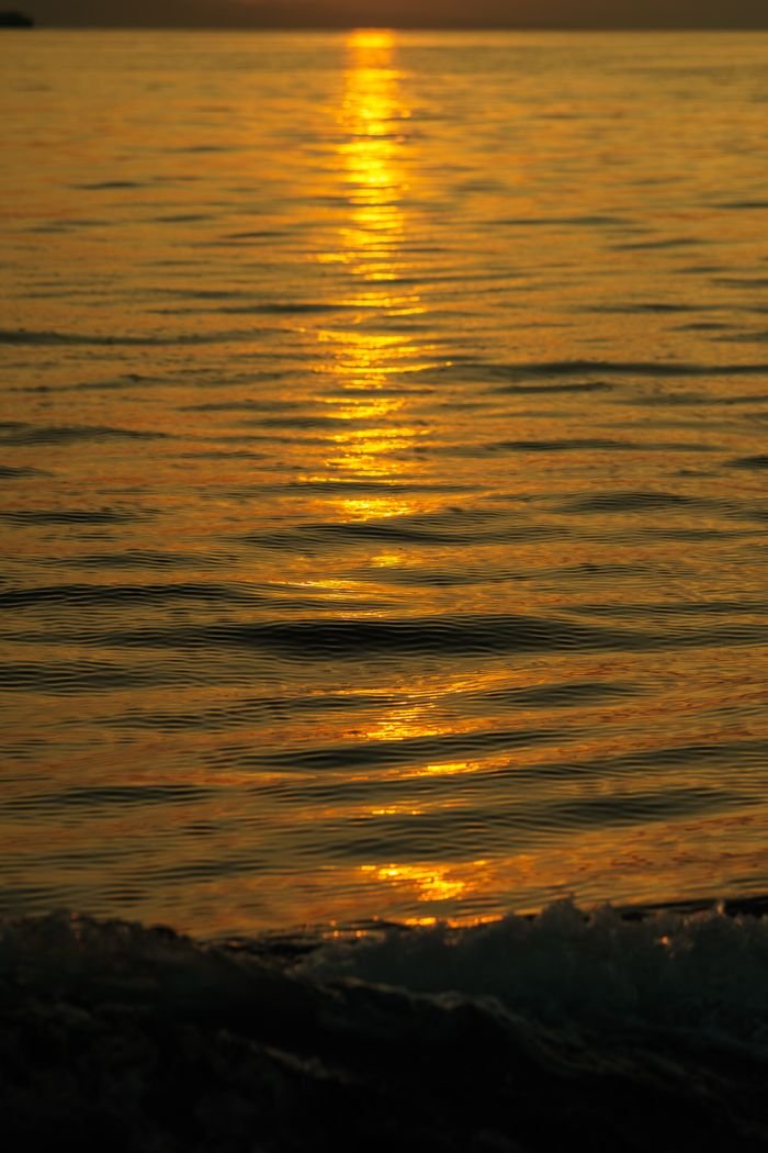 Captivating golden sunset reflections over ocean waves create a serene and calming atmosphere.